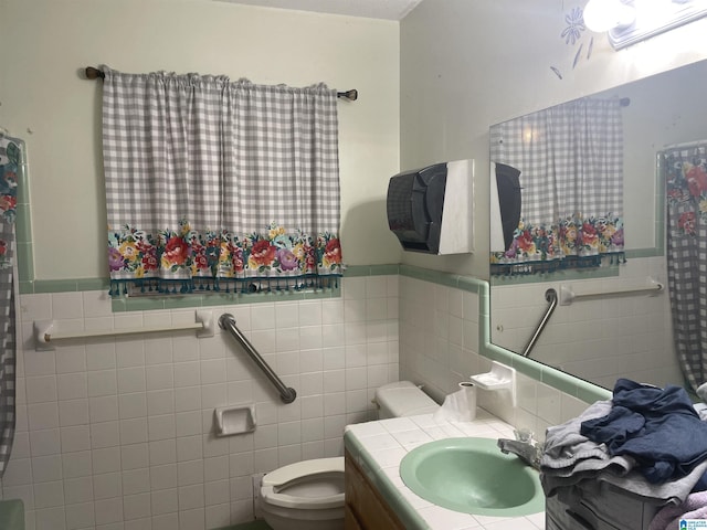 bathroom with vanity, toilet, and tile walls