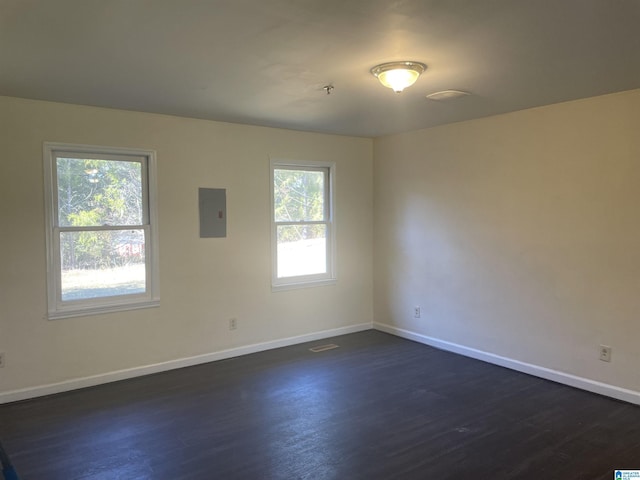 unfurnished room featuring electric panel and dark hardwood / wood-style floors