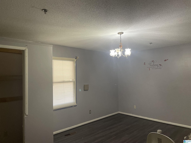 unfurnished room featuring a textured ceiling, dark hardwood / wood-style floors, and a notable chandelier