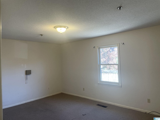 empty room with a textured ceiling and dark colored carpet