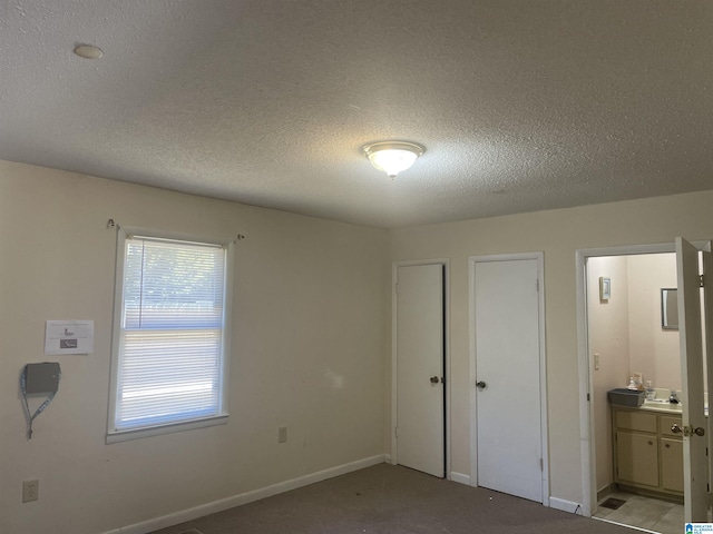 unfurnished bedroom featuring sink, a textured ceiling, and ensuite bath