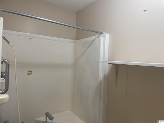 bathroom with a shower and a textured ceiling