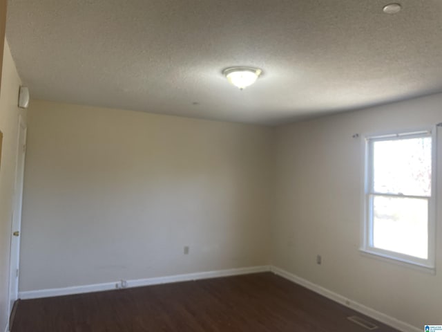 spare room with dark hardwood / wood-style floors and a textured ceiling