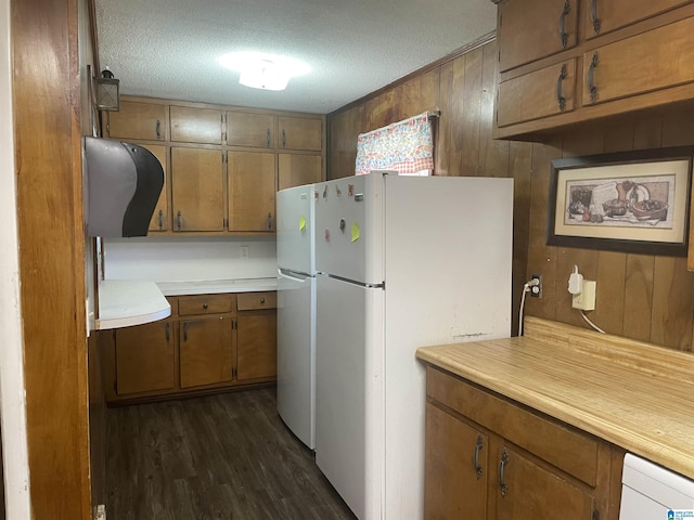 kitchen featuring wood walls, white fridge, dark wood-type flooring, and a textured ceiling