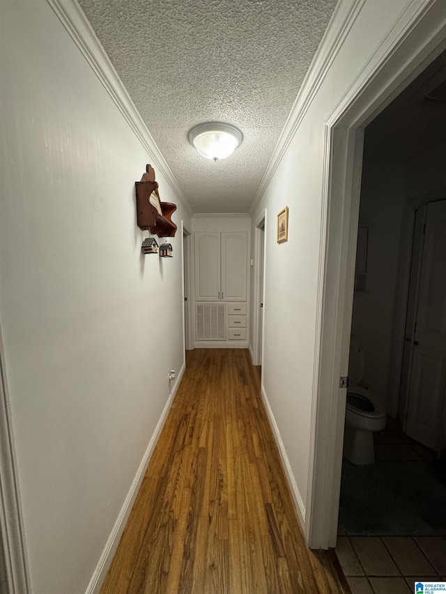 corridor with crown molding, hardwood / wood-style floors, and a textured ceiling