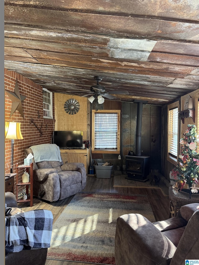 living room with hardwood / wood-style flooring, a wood stove, a wealth of natural light, and ceiling fan