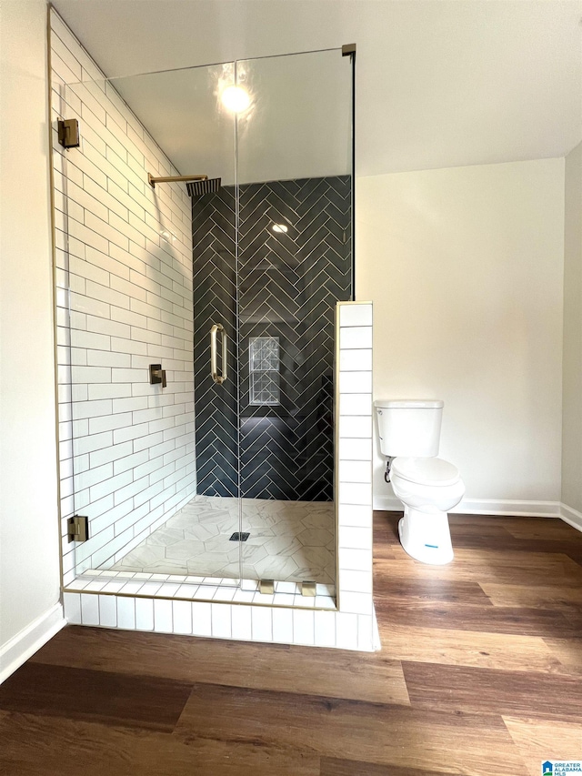 bathroom with hardwood / wood-style floors, toilet, and an enclosed shower