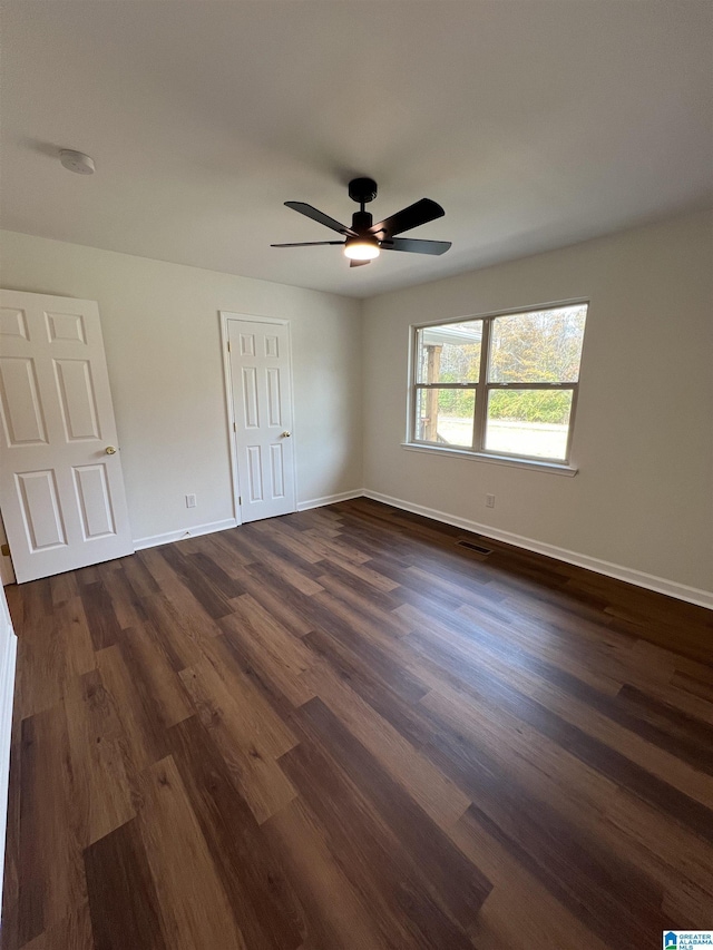 empty room with dark hardwood / wood-style flooring and ceiling fan