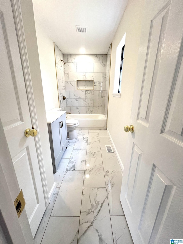 full bathroom with toilet, vanity, and tiled shower / bath