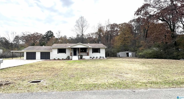 single story home with a porch, a garage, a front lawn, and a storage shed