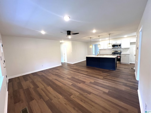 kitchen featuring dark hardwood / wood-style floors, an island with sink, decorative light fixtures, white cabinetry, and stainless steel appliances