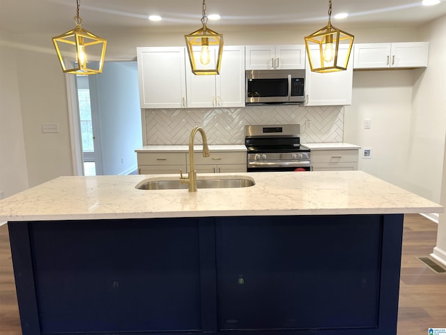 kitchen with light stone countertops, stainless steel appliances, sink, pendant lighting, and white cabinets