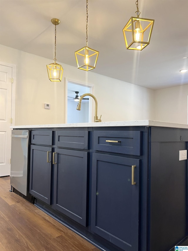 bar with dark hardwood / wood-style flooring, blue cabinets, hanging light fixtures, and sink