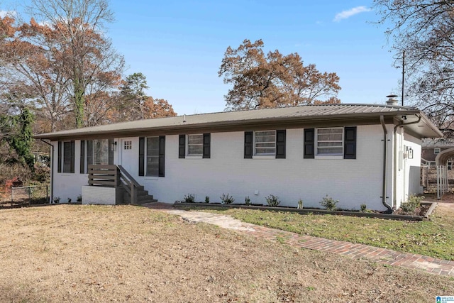 ranch-style house with metal roof, brick siding, and a front yard