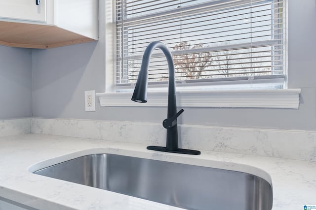 room details featuring light stone countertops and sink