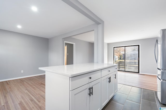 kitchen with a center island, light hardwood / wood-style floors, stainless steel refrigerator, and white cabinetry