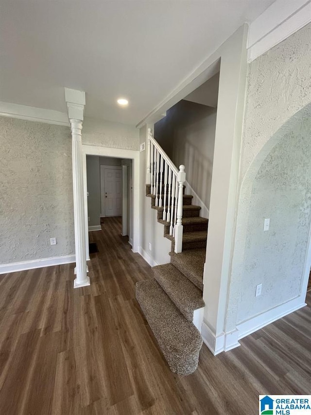 stairway with wood-type flooring and decorative columns