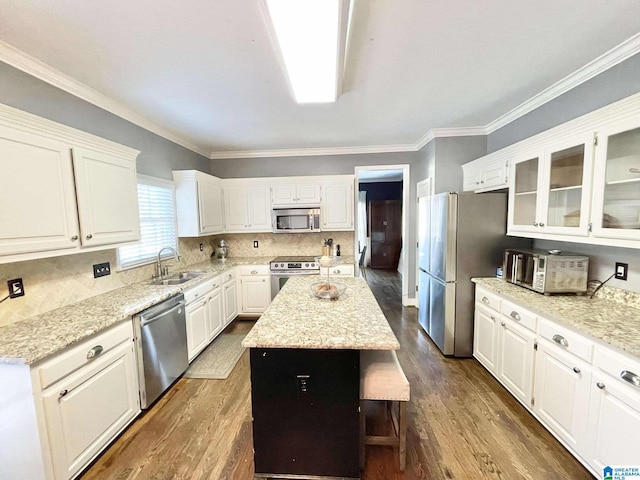 kitchen with dark hardwood / wood-style flooring, stainless steel appliances, sink, white cabinets, and a center island