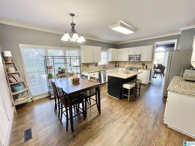 dining area with hardwood / wood-style flooring, an inviting chandelier, ornamental molding, and sink