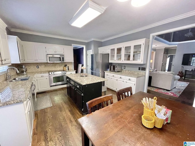 kitchen with stainless steel appliances, sink, hardwood / wood-style floors, a center island, and white cabinetry