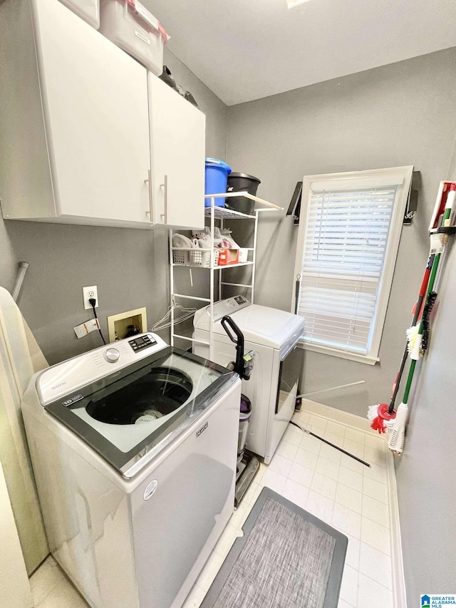 clothes washing area with cabinets, separate washer and dryer, and light tile patterned floors