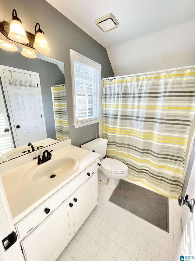 bathroom with tile patterned flooring, vanity, lofted ceiling, and toilet