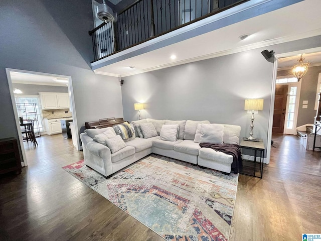 living room featuring hardwood / wood-style flooring, a towering ceiling, ornamental molding, and a chandelier