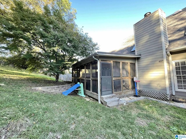 view of side of home with a sunroom and a lawn