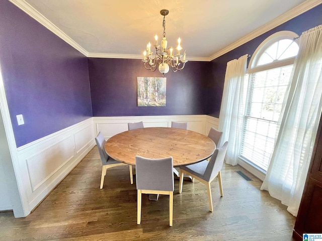 dining area with an inviting chandelier, ornamental molding, and hardwood / wood-style flooring