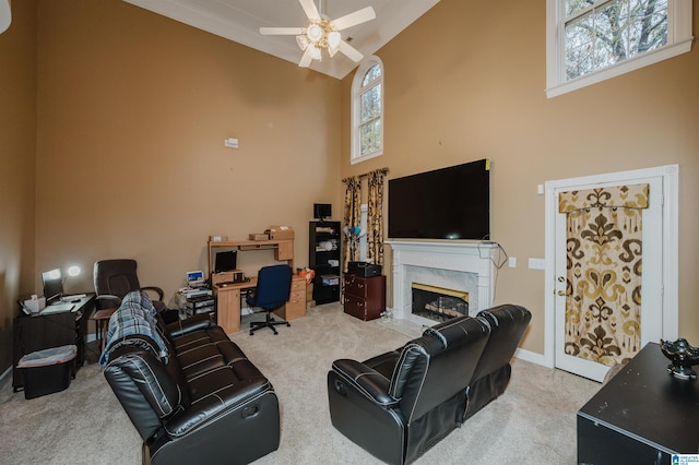 carpeted living room with a high end fireplace, ceiling fan, and high vaulted ceiling