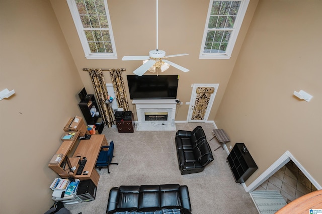 carpeted living room featuring ceiling fan, a high end fireplace, and a high ceiling