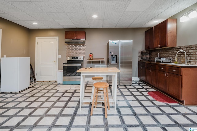 kitchen with tasteful backsplash, sink, stainless steel appliances, and a drop ceiling