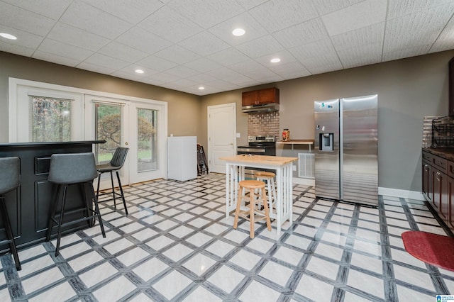 kitchen with a kitchen bar, appliances with stainless steel finishes, and decorative backsplash