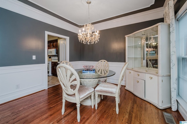 dining area with ornamental molding, dark wood-type flooring, and a chandelier