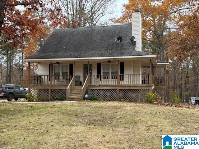 farmhouse-style home with covered porch, ceiling fan, and a front yard