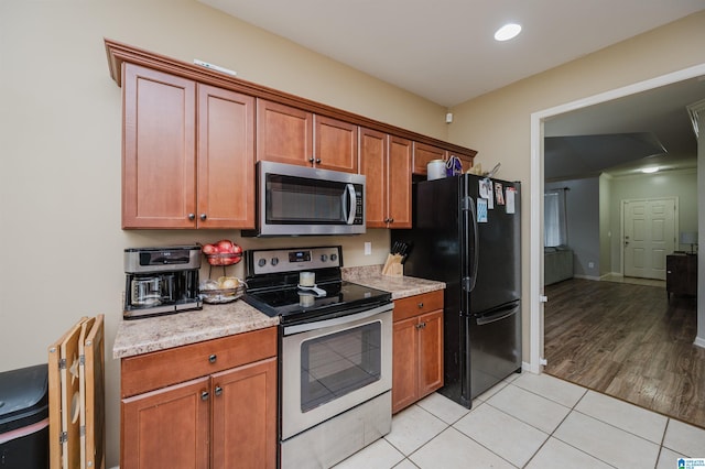 kitchen with light hardwood / wood-style floors, light stone counters, and stainless steel appliances