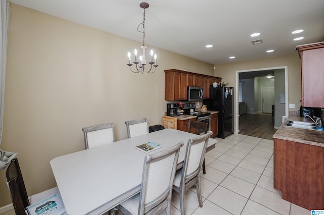 dining space with sink, light hardwood / wood-style floors, and a notable chandelier