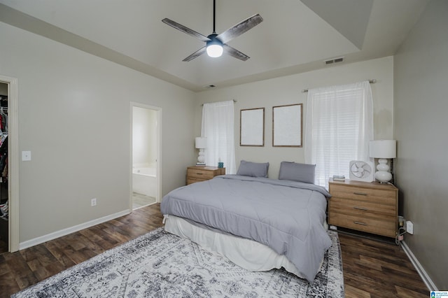 bedroom with dark hardwood / wood-style flooring, connected bathroom, a spacious closet, and ceiling fan