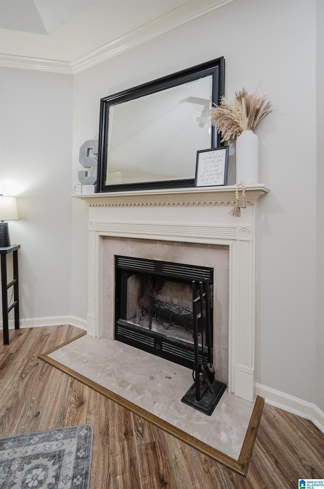 interior details with a fireplace, wood-type flooring, and crown molding