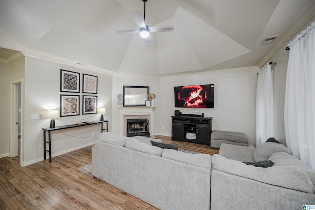 living room featuring light hardwood / wood-style floors, vaulted ceiling, ceiling fan, and ornamental molding