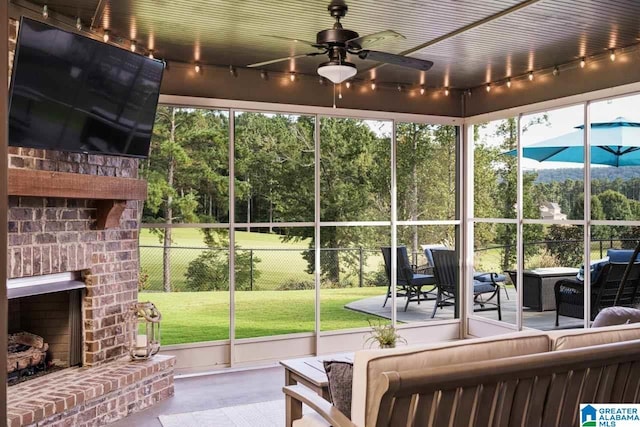 sunroom / solarium featuring an outdoor brick fireplace, ceiling fan, plenty of natural light, and rail lighting