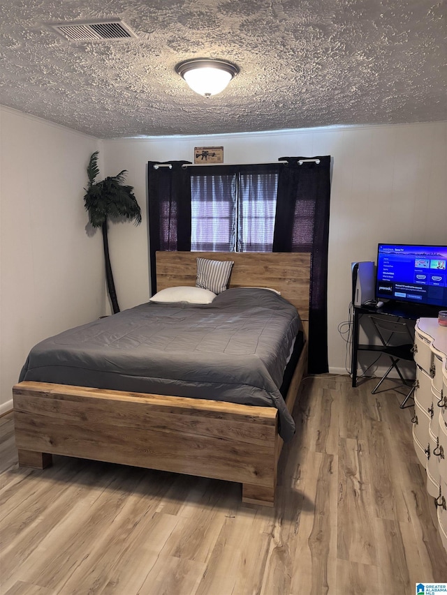 bedroom featuring a textured ceiling and light hardwood / wood-style flooring