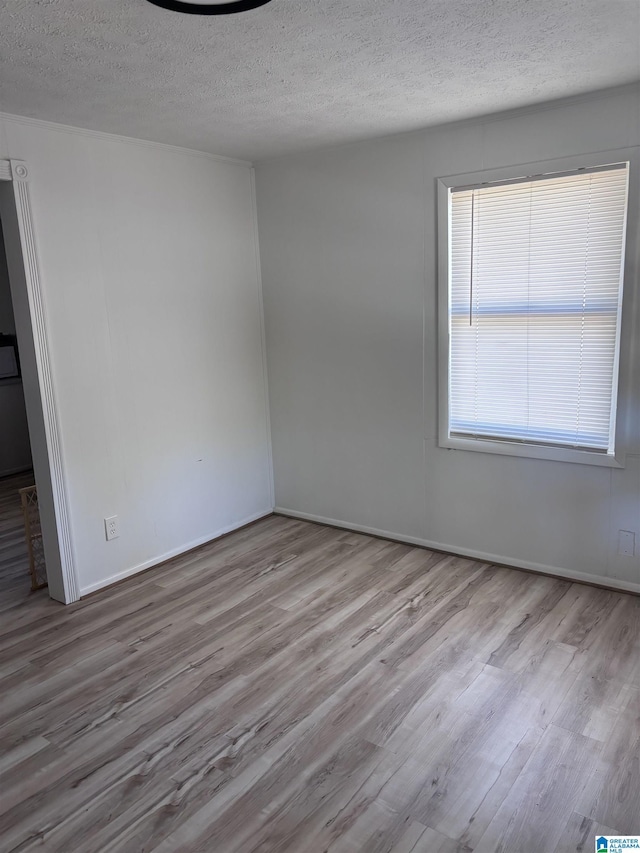 unfurnished room featuring light hardwood / wood-style floors and a textured ceiling