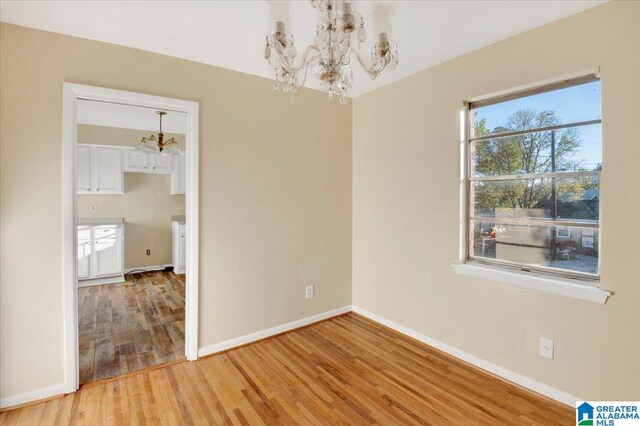 empty room featuring hardwood / wood-style flooring and a notable chandelier