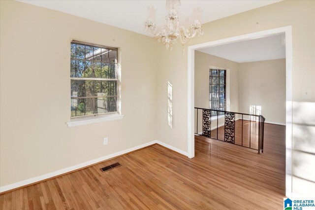 unfurnished room with hardwood / wood-style flooring and a chandelier