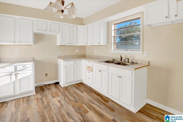 kitchen featuring white cabinets, an inviting chandelier, light hardwood / wood-style flooring, and sink