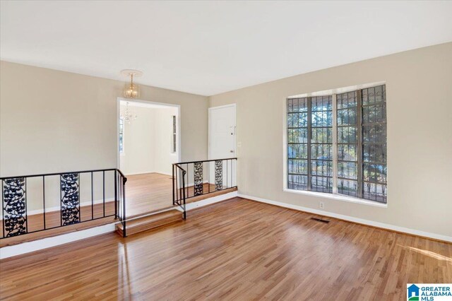 unfurnished room with a chandelier and hardwood / wood-style flooring