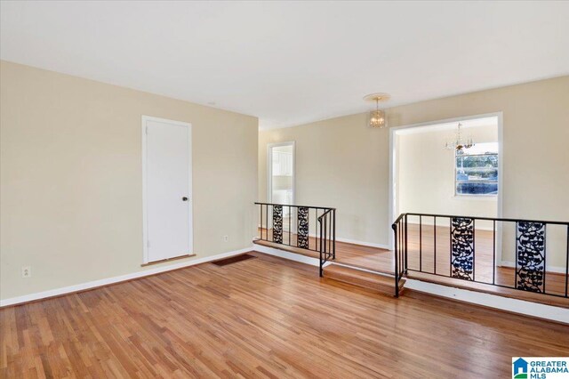 spare room featuring a chandelier and hardwood / wood-style flooring