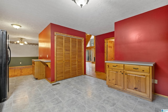 kitchen with black fridge and a textured ceiling