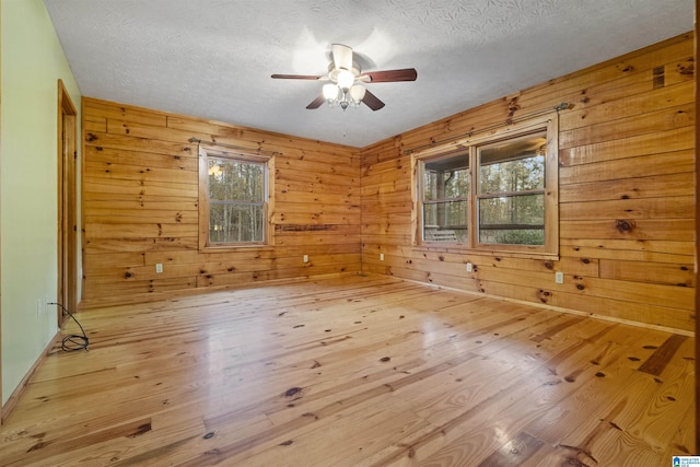 empty room featuring hardwood / wood-style floors, a healthy amount of sunlight, and wooden walls